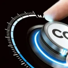 Dłoń obraca pokrętło z napisem CO2, zmniejszając emisje. Skala wskazuje na redukcję.