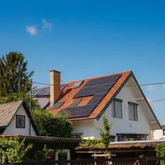 Domy z panelami słonecznymi na dachach, symbolizujące odnawialne źródła energii.